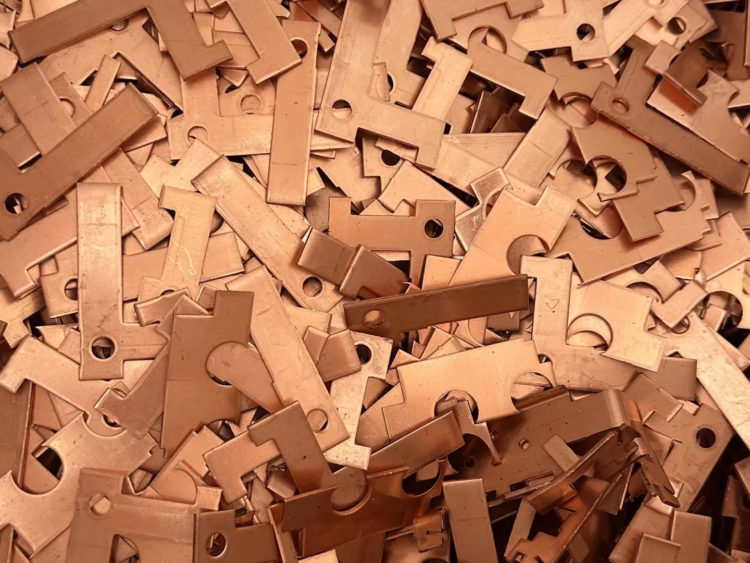 Accumulation de chutes de découpe en métal cuivré avec diverses formes géométriques et perforations circulaires